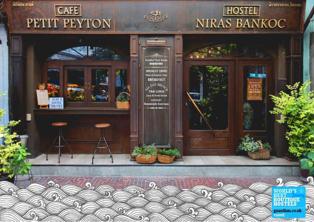 a store front of a restaurant with potted plants at Niras Bankoc Hostel in Bangkok