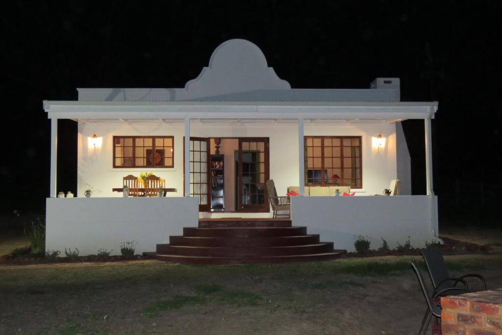 a white house with a porch at night at Out of Plett in Plettenberg Bay