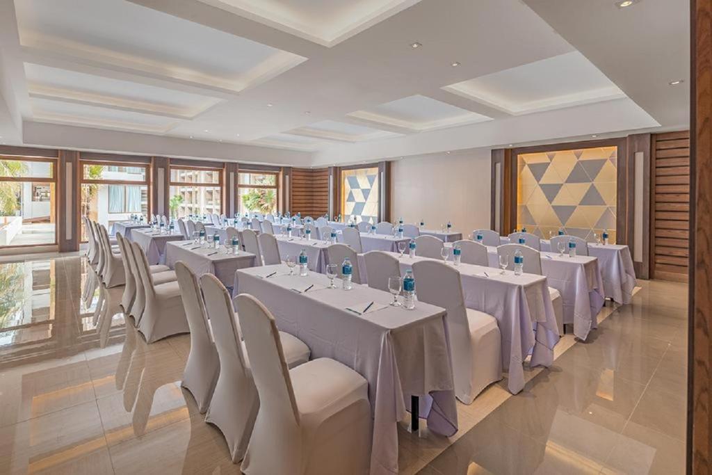 a banquet hall with white tables and chairs and windows at Henann Crystal Sands Resort in Boracay