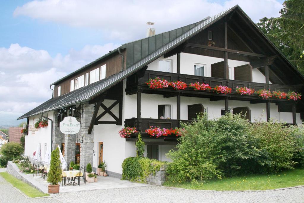 ein weißes und schwarzes Gebäude mit roten Blumen in der Unterkunft Hotel zum Friedl in Riedlhütte