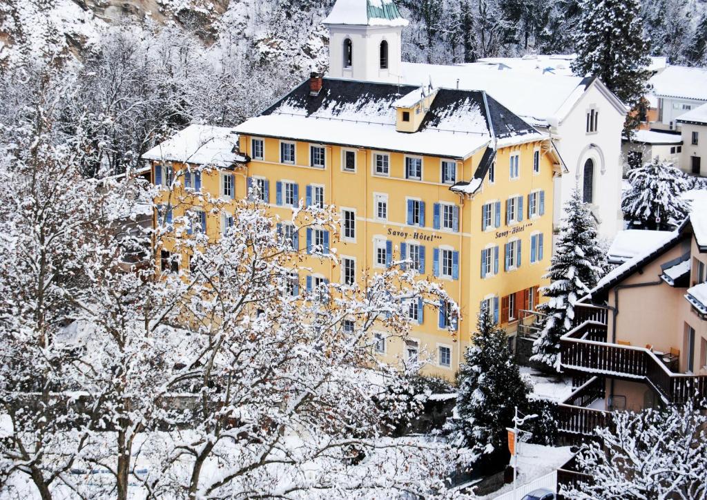 a yellow building covered in snow in a town at Savoy Hôtel in Brides-les-Bains