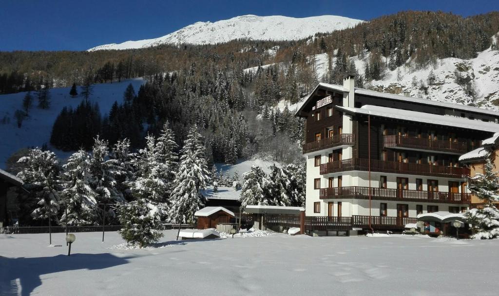 a large building in the snow in front of a mountain at Residence Les Coupoles in Champoluc