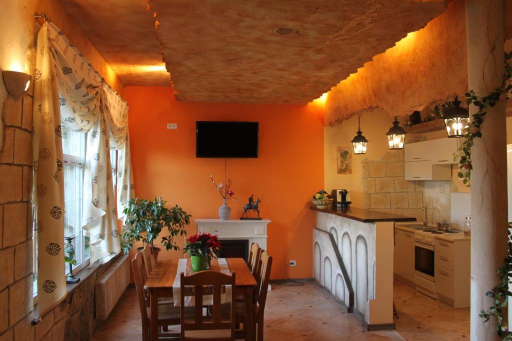 a kitchen with orange walls and a table and chairs at Apartamenty Vesuvio in Dźwirzyno