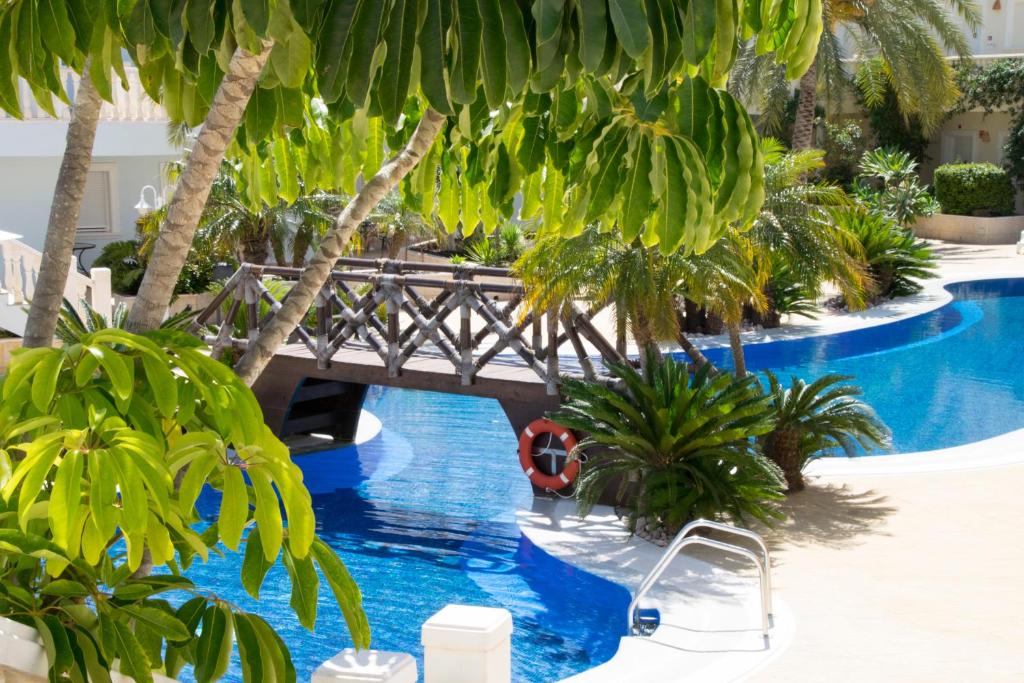 a bridge over a swimming pool with palm trees at Hotel Apartamento Residencia Parques Casablanca in Benissa