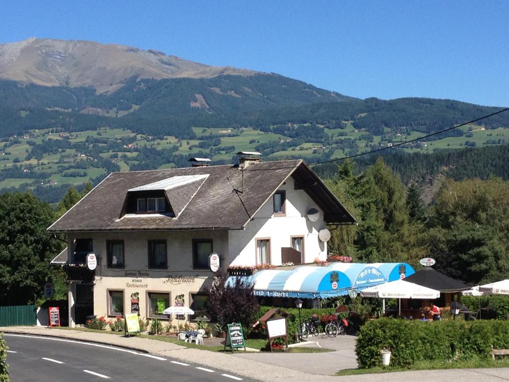 un bâtiment situé sur le côté d'une route avec une montagne dans l'établissement Gasthof-Pension Reidnwirt, à Baldramsdorf