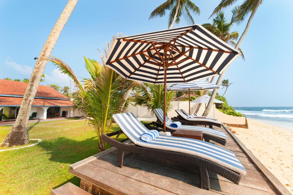 un gruppo di sedie e un ombrellone in spiaggia di Isle of Thalpe a Unawatuna