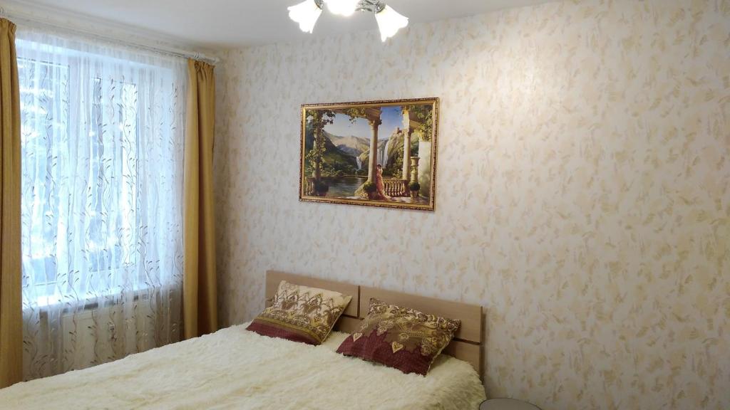 ペルミにあるStudio u Permskoy Yarmarkiのベッドルーム1室(ベッド1台付)が備わります。壁に絵が飾られています。