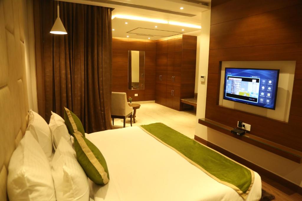 a hotel room with a bed and a flat screen tv at Maple Grand in Agra