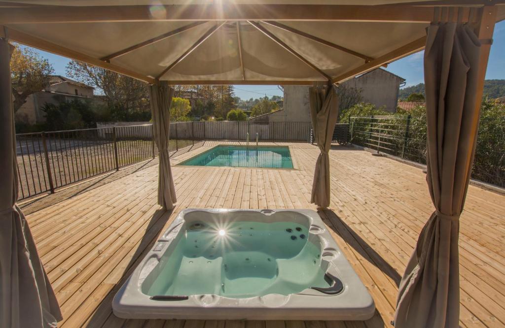 a hot tub in a gazebo on a deck at Hotel Restaurant Le Castel Fleuri in Carnoules