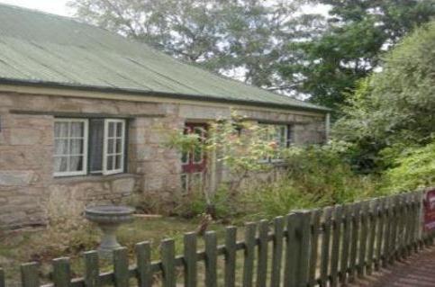 a stone house with a fence in front of it at Colonial Cottages of Ross in Ross