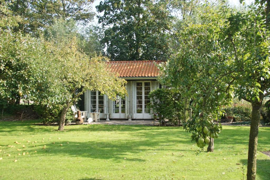een huis in een tuin met bomen ervoor bij Vakantiehuizen Kats Zeeland De Zwaluwenhof in Kats