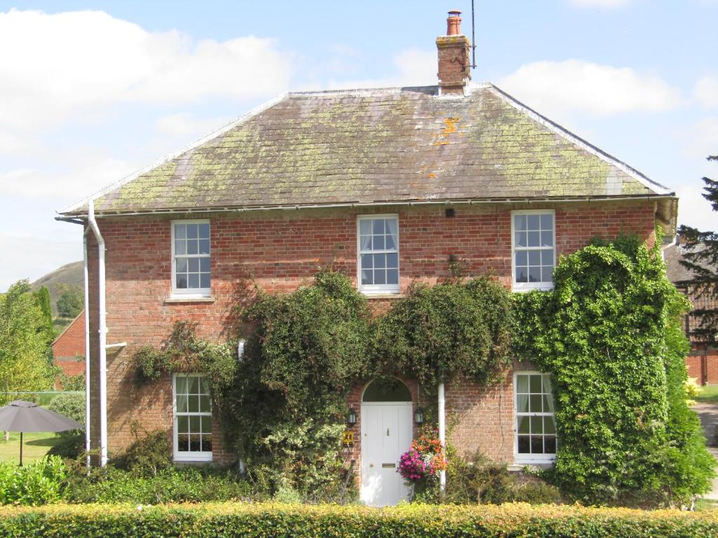 uma casa de tijolos vermelhos com uma porta branca em Home Farm Boreham em Warminster