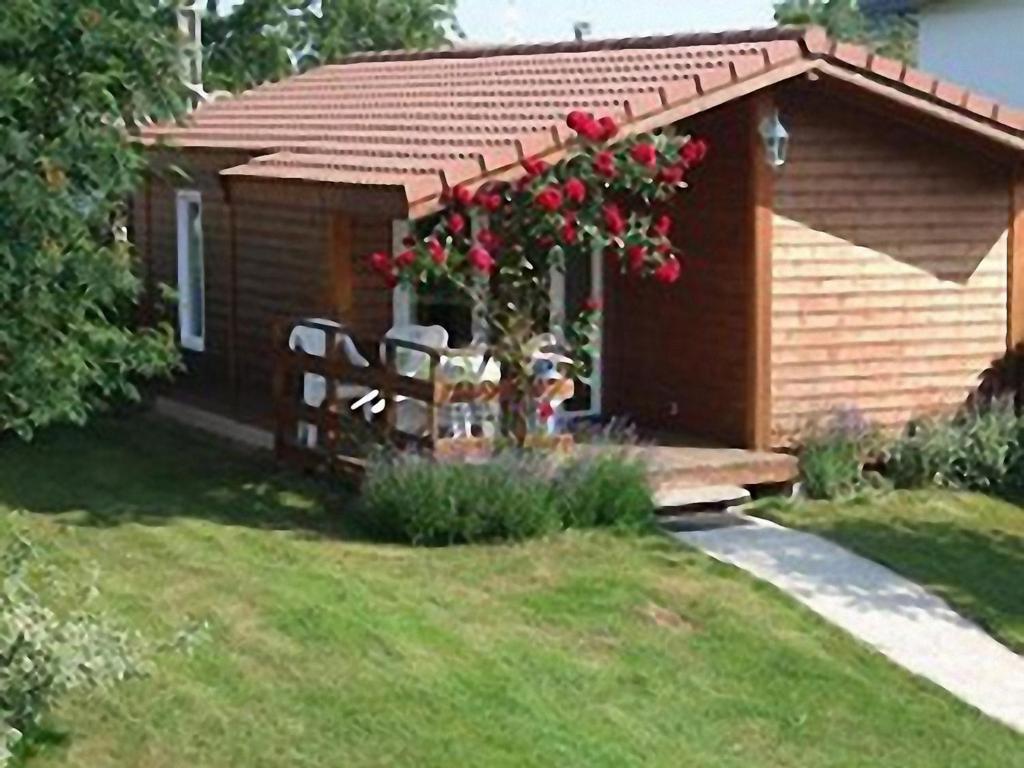 uma pequena cabana com duas cadeiras e uma árvore com rosas vermelhas em Camping Fraiteux em Plombières-les-Bains