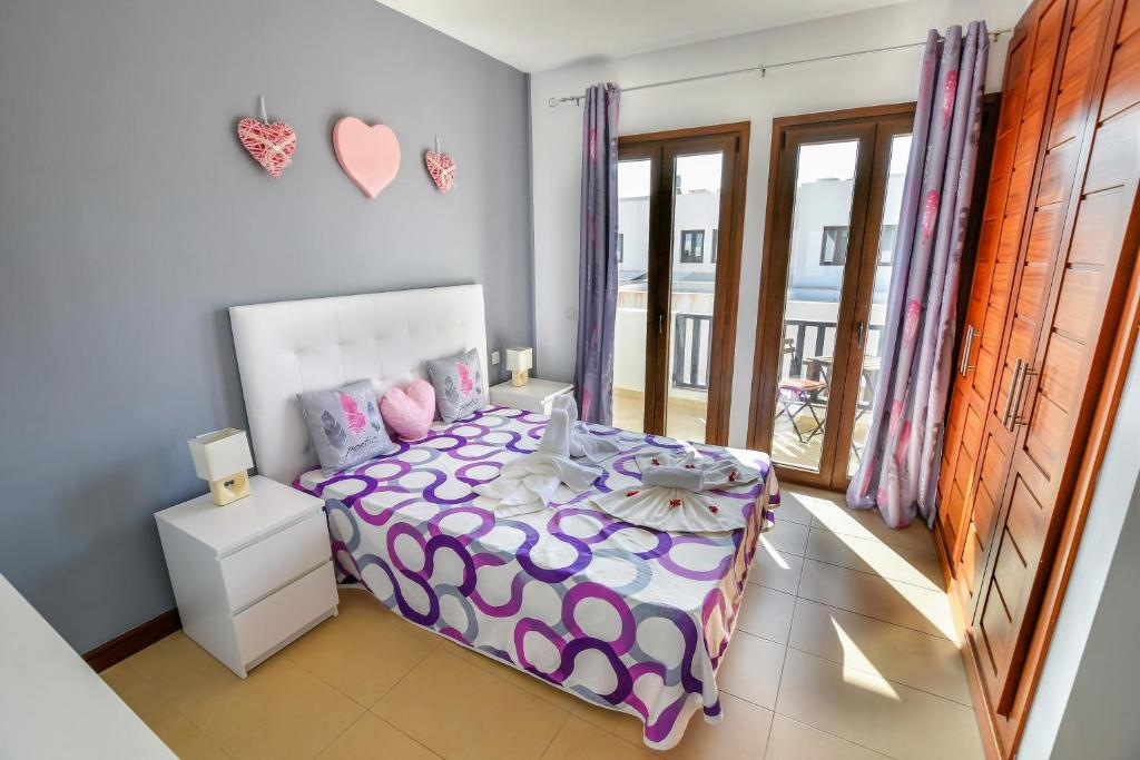 a bedroom with a bed with a purple comforter at Casa Zen in Puerto Calero
