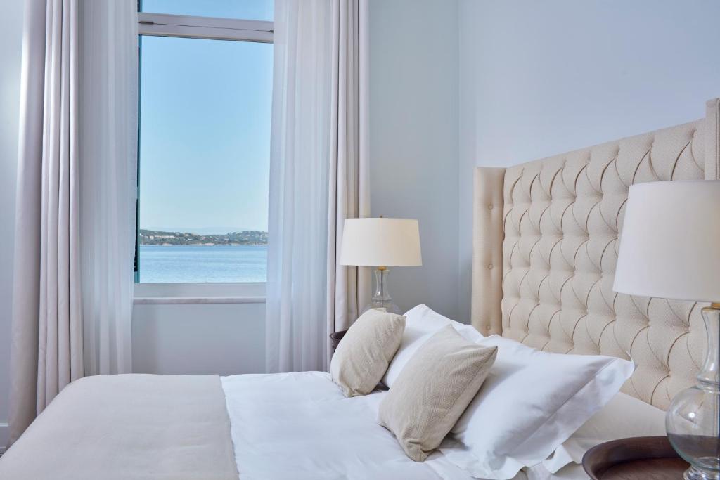 a bedroom with a white bed with a window at Poseidonion Grand Hotel in Spetses