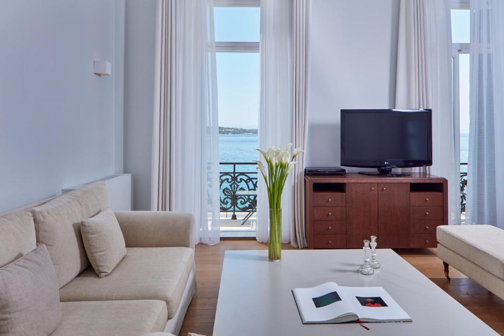 a living room with a couch and a tv at Poseidonion Grand Hotel in Spetses