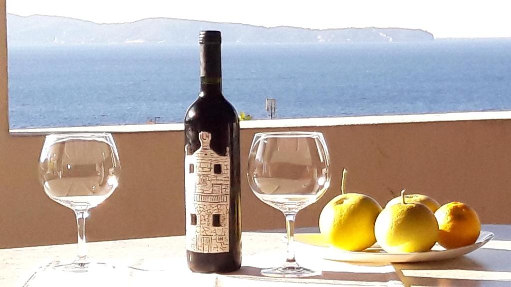 a bottle of wine next to two glasses of pears at Apartments Bako Komiza in Komiža