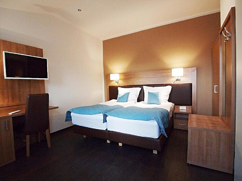 ein Hotelzimmer mit einem großen Bett und einem Schreibtisch in der Unterkunft Sporthotel Dorum in Dorum