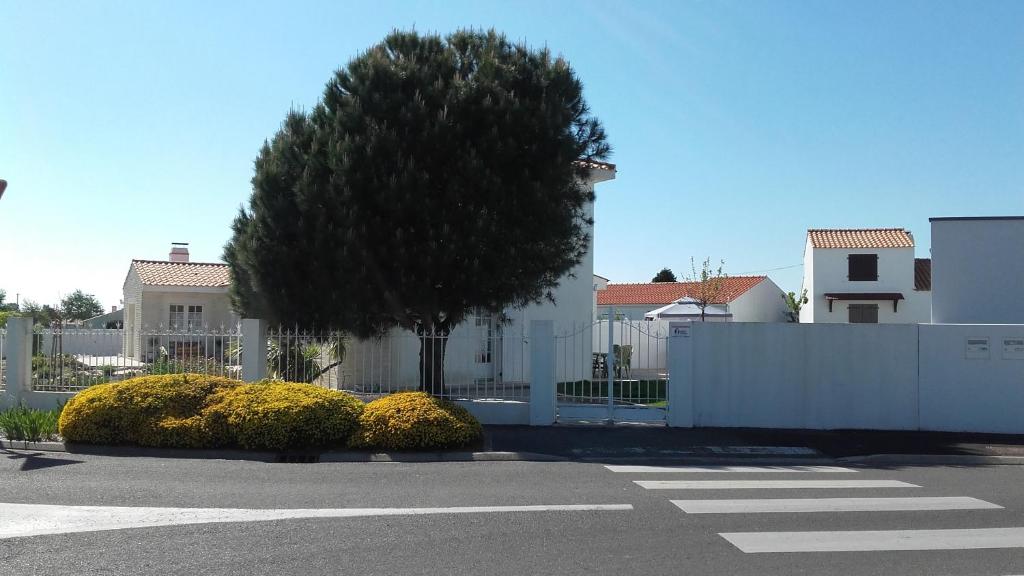 a white fence with a tree in front of a house at Maison avec Jardin privé in Saint-Hilaire-de-Riez