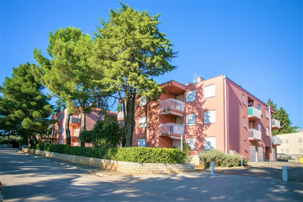 a pink building with trees next to a street at Apartment Morena in Novigrad Istria