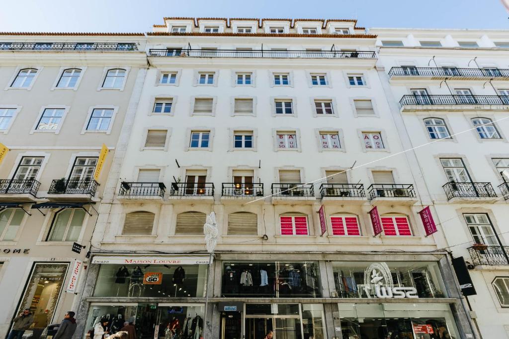 - un grand bâtiment blanc avec des fenêtres et des balcons dans l'établissement Carmo Apartments, à Lisbonne