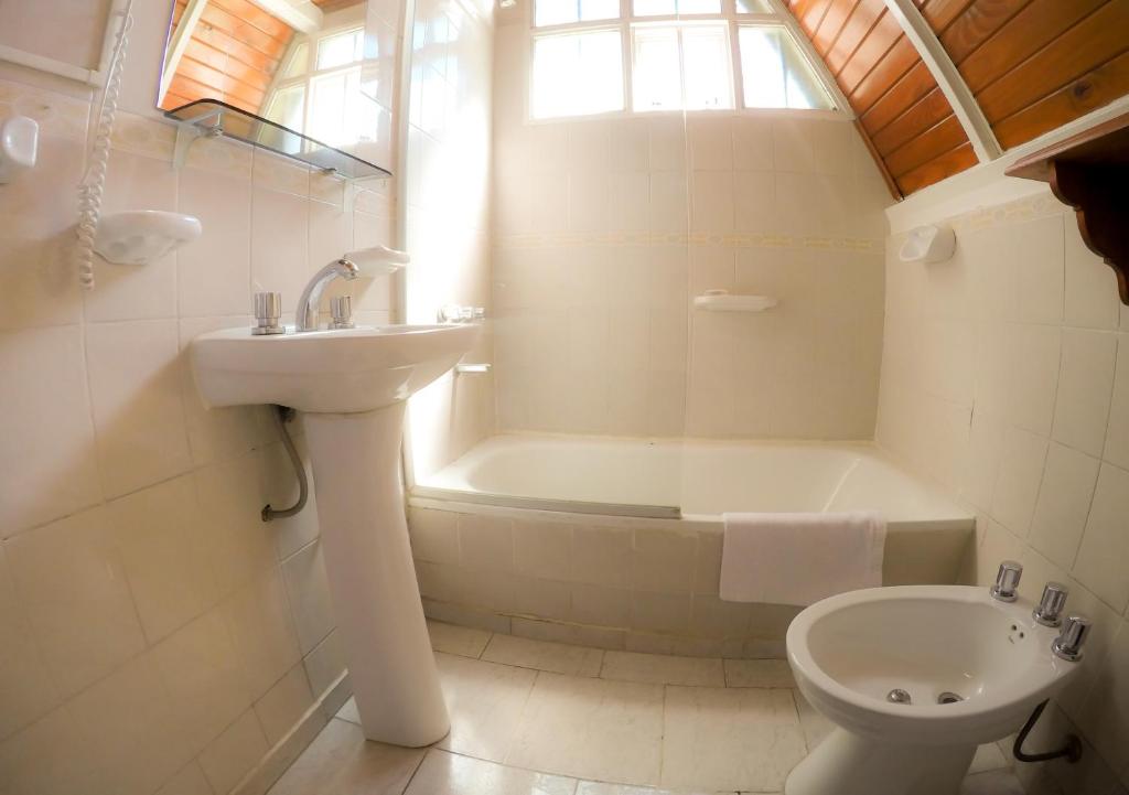 a bathroom with a sink and a toilet and a tub at Apart Hotel Ensueño in San Martín de los Andes