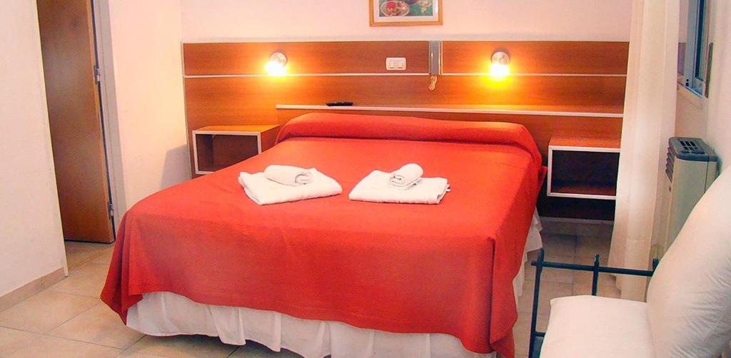 a bedroom with a red bed with two towels on it at Hotel Playa in Villa Carlos Paz
