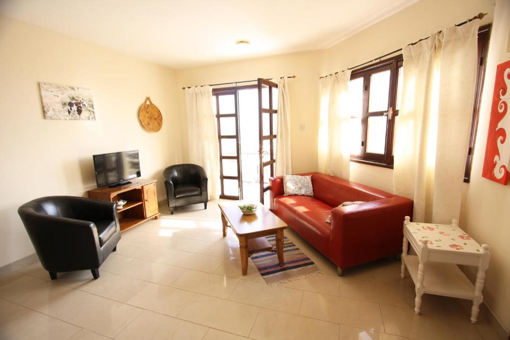 a living room with a red couch and a table at Sea View Apartments in Pissouri