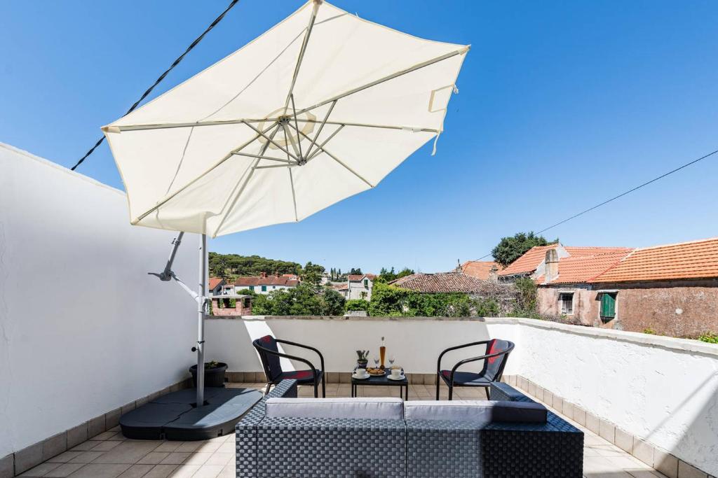 eine Terrasse mit einem Sonnenschirm, einem Tisch und Stühlen in der Unterkunft Apartment Pjaca in Postira