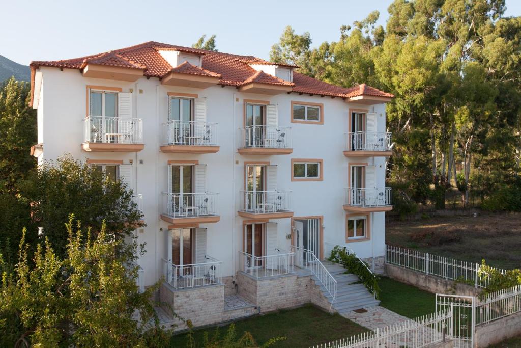 a large white building with balconies and trees at Elatos Apartments in Klitoria