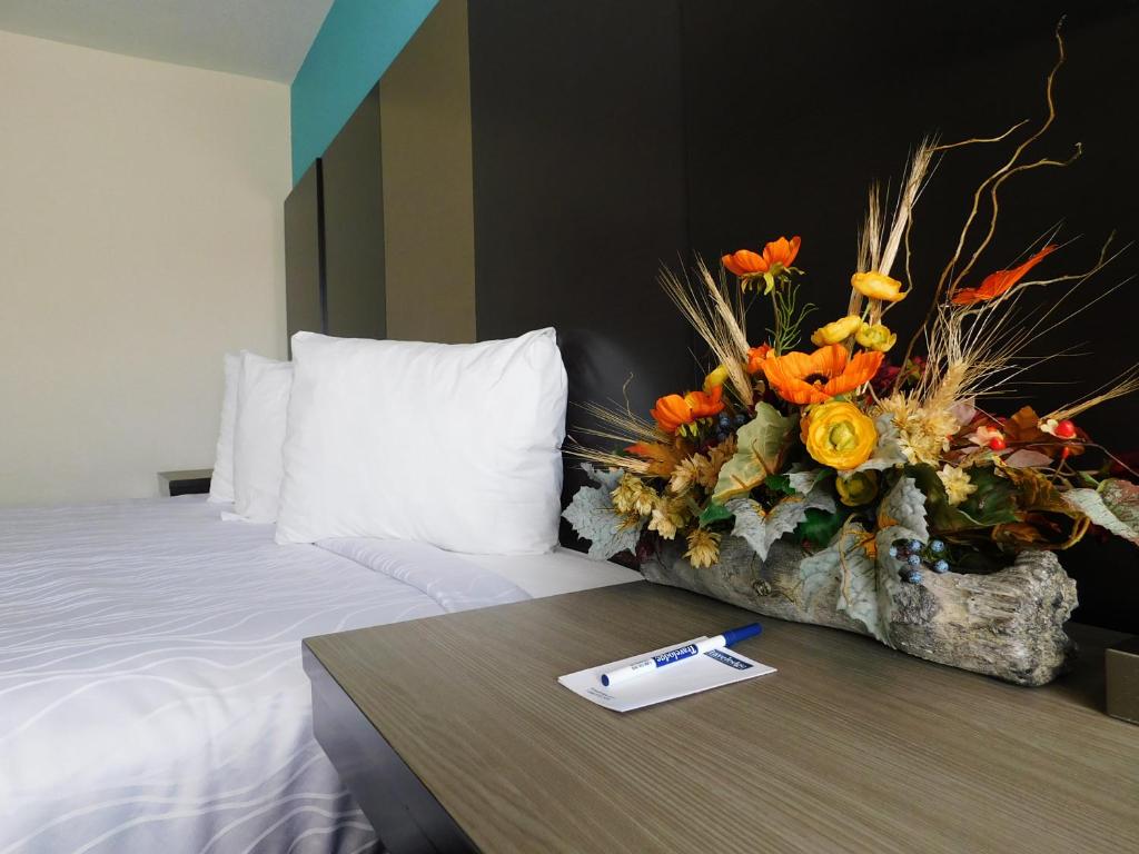 a hotel room with a bed and a table with a flower arrangement at Travelodge by Wyndham Angels Camp CA in Angels Camp