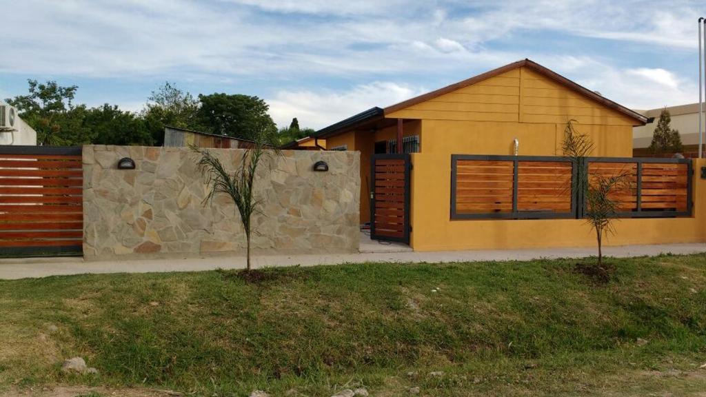 uma casa amarela com uma parede de pedra em Las Casitas de Emilia em Ramallo