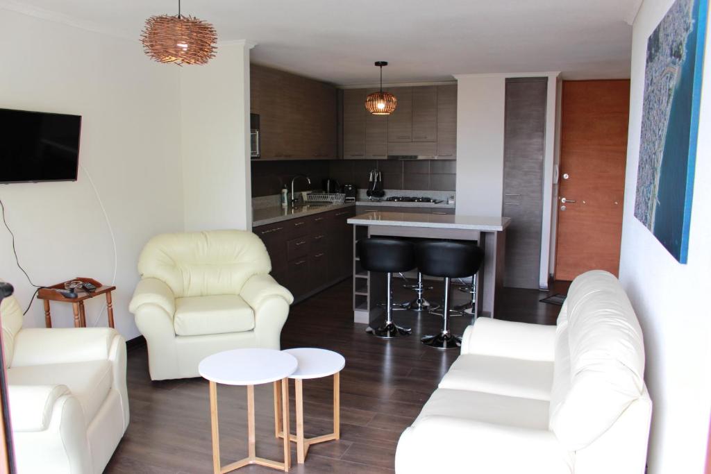 a living room with white furniture and a kitchen at Departamentos Parts Concepción in Concepción