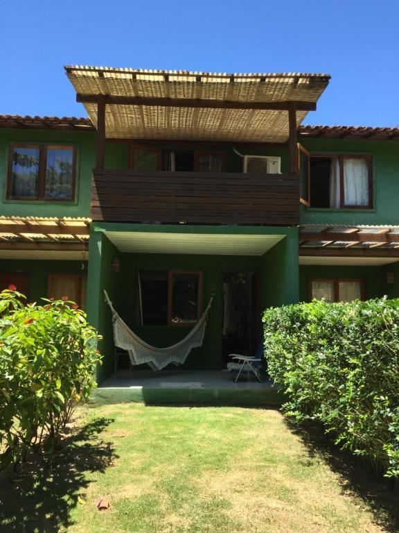 una casa verde con una hamaca en el patio en Casa Aconchego - Arraial D Ajuda- Bahia, en Arraial d'Ajuda