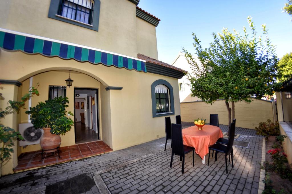 eine Terrasse mit einem Tisch und Stühlen vor einem Haus in der Unterkunft Chalet El Naranjo in Sevilla