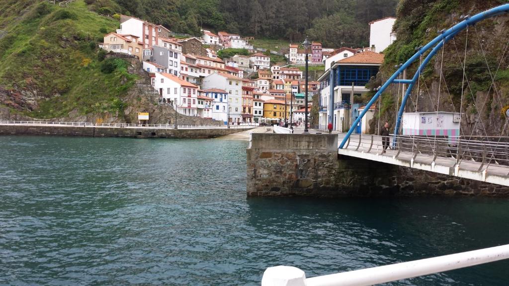 a bridge over a river with houses on a hill at Casina del Puerto in Cudillero