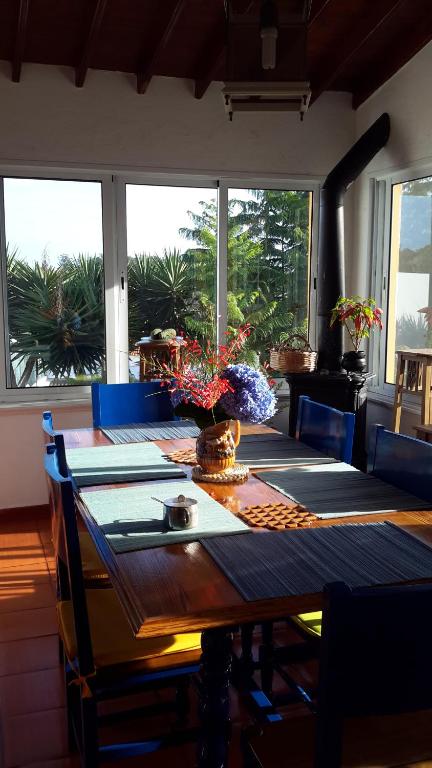 a dining room with a table with chairs and windows at Ponta Delgada - Casa Rural in Ponta Delgada