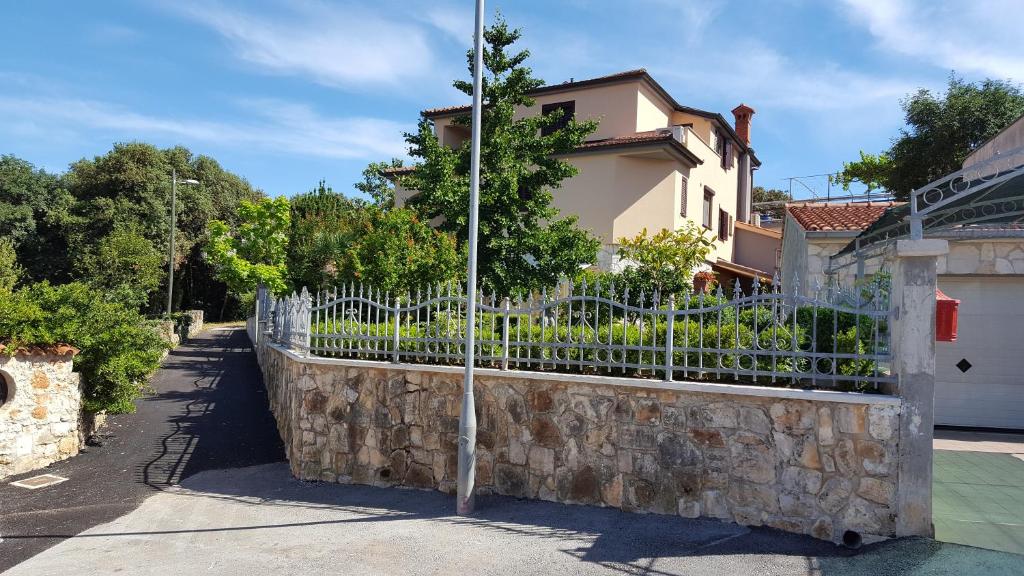 a fence in front of a building with a stone wall at Apartments Ginkgo in Banjole