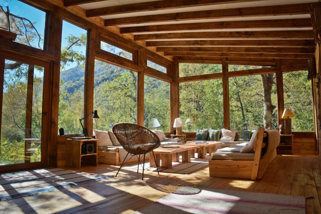 a living room with large windows in a cabin at Onai Hostel in Las Trancas