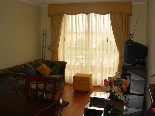 sala de estar con sofá y ventana en Departamento en la Serena, en La Serena