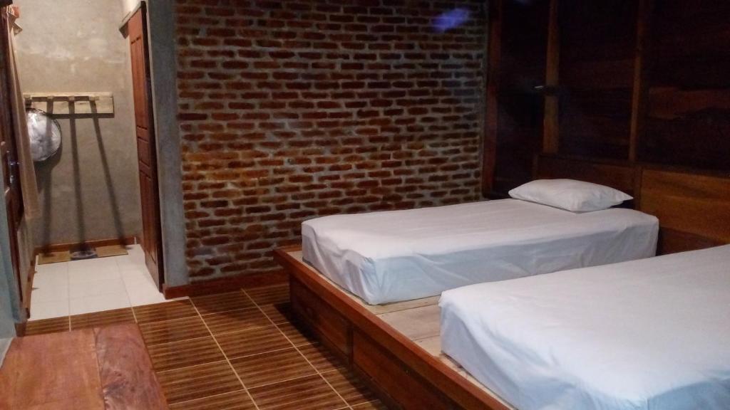 two beds in a room with a brick wall at Dolin Cottage in Hilibotodane
