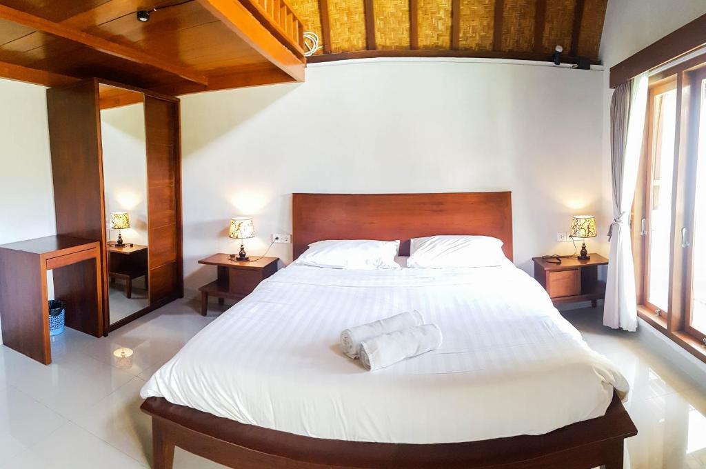 a bedroom with a large white bed with two night stands at Naturela in Uluwatu