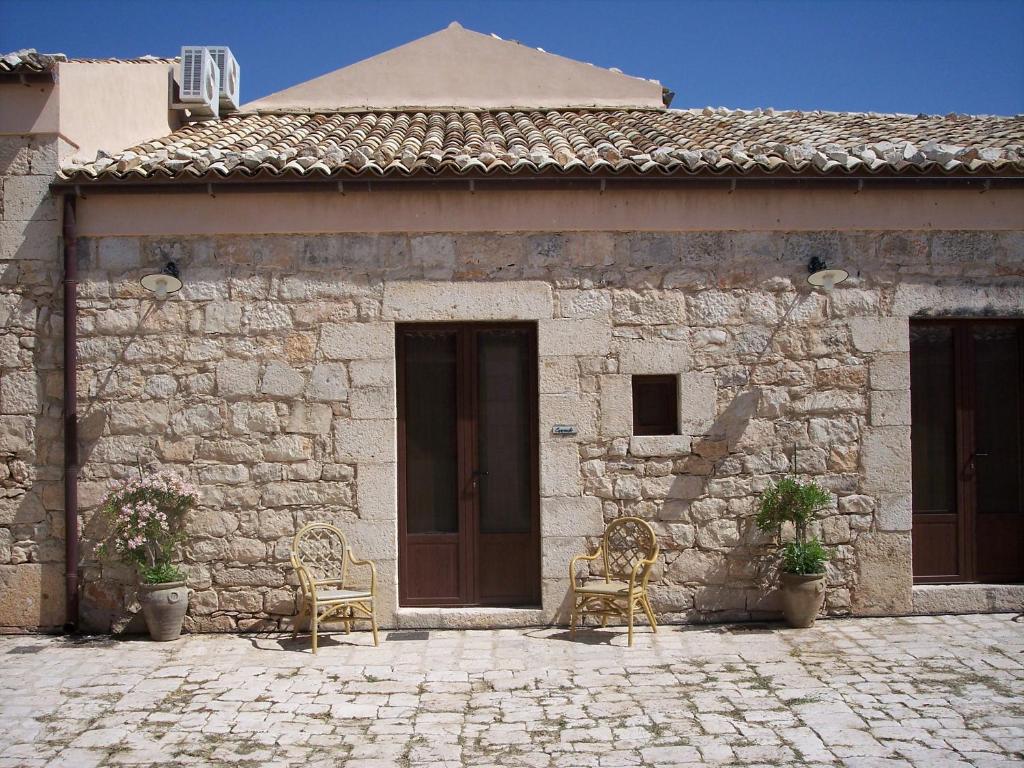 un edificio in pietra con due sedie davanti di Case di Cutalia - Villa Cutalia a Camemi