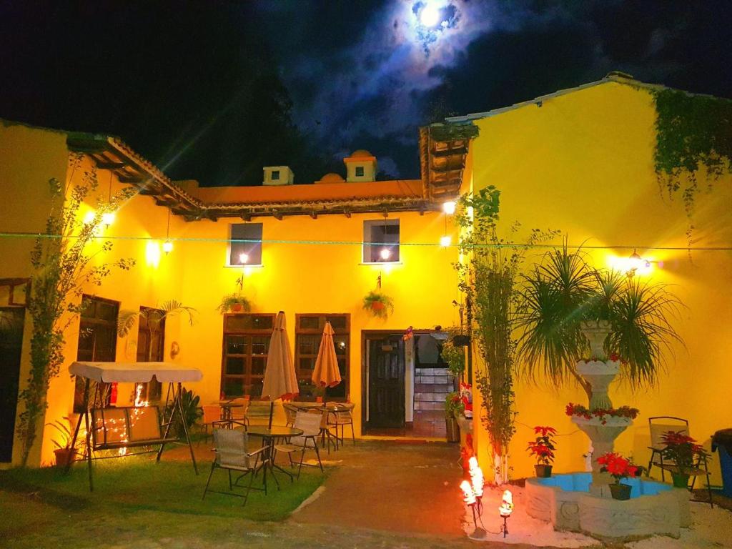 Maison jaune avec patio la nuit dans l'établissement Hotel Casa del Cerro, à Antigua Guatemala