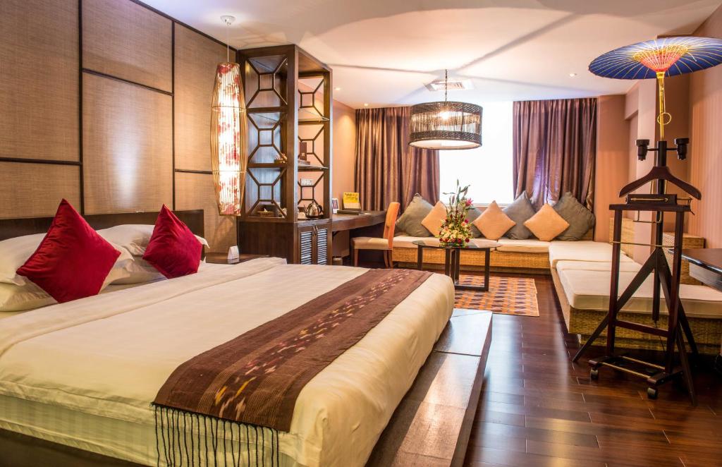 a bedroom with a large bed and a couch at Rose Garden Hotel in Yangon