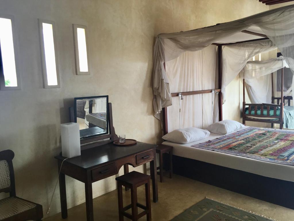 
a bedroom with a bed and a desk at Subira House in Lamu
