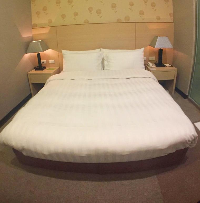 a large white bed in a hotel room with two lamps at Royal Hotel in Taipei