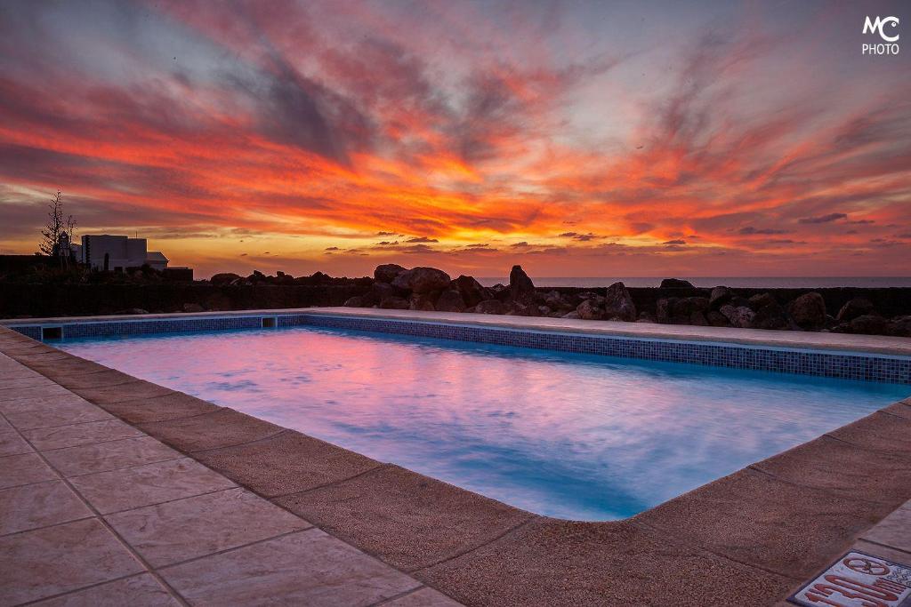 a swimming pool with a sunset in the background at Villa Hortensia in Playa Blanca