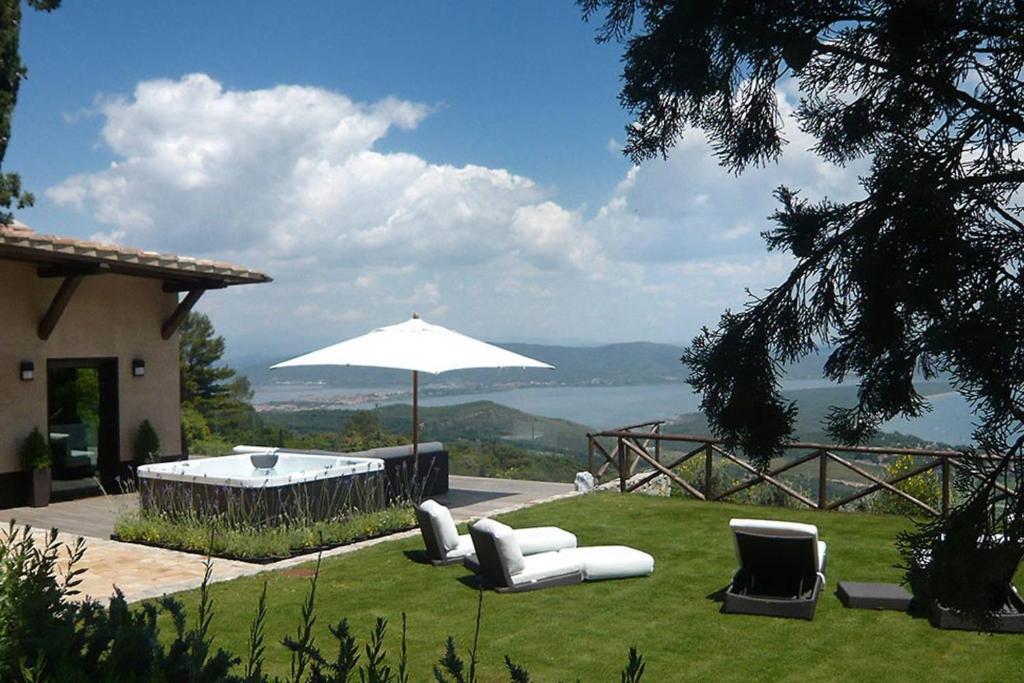 eine Liegewiese mit Stühlen, einem Sonnenschirm und einem Pool in der Unterkunft Villaflair - Design Villa Porto Ercole in Monte Argentario