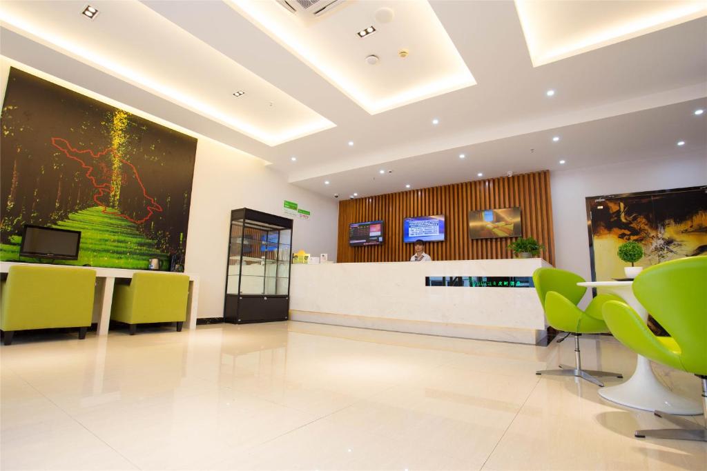 an office lobby with green chairs and a large painting at Vatica Suzhou Yongqiao District Yinhe 2 Road Wanda Plaza Hotel in Suzhou